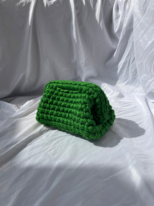 Bright green hand-crocheted Truffle Mini Clutch by LISSA on a white fabric background