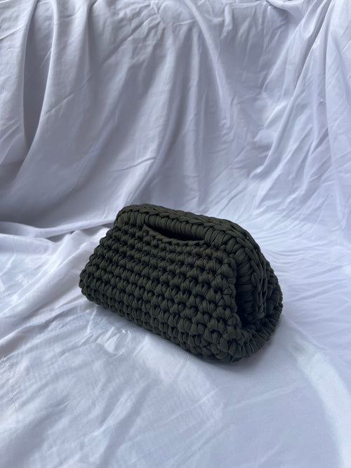 Olive green hand-crocheted Truffle Mini Clutch by LISSA on a white fabric background